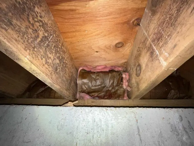 An image showing a dark, cluttered, and damaged attic space with insulation and debris visible.