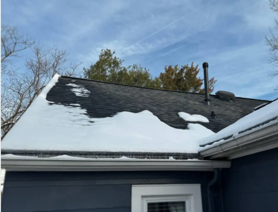 A snowy roof with icicles hanging from the edge forming an ice dam