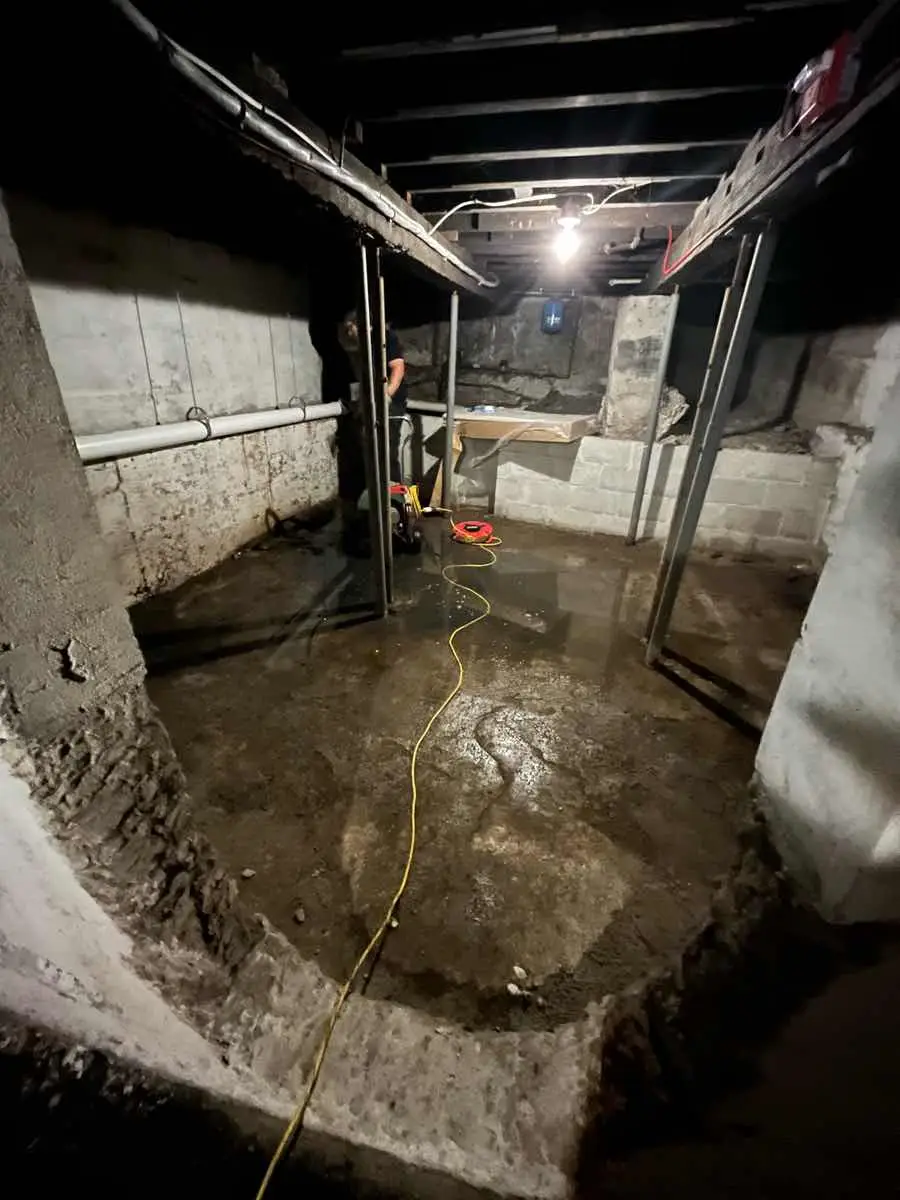 A dark, flooded basement with debris and equipment visible, showing the need for a sump pump.