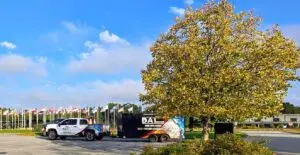 A pickup truck with the DAT logo and graphics parked in a lot surrounded by trees and flags.