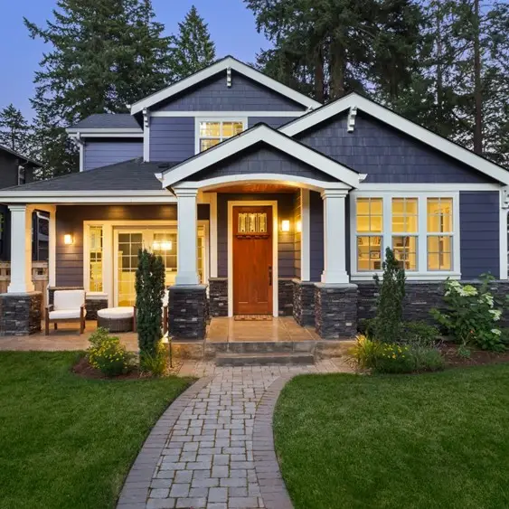 A home property with it's lights on and a well designed exterior that looks homey and welcoming