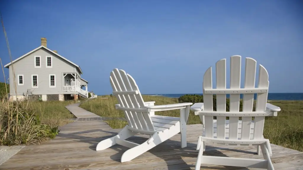 A rental property set on a beach with two chairs in the foreground